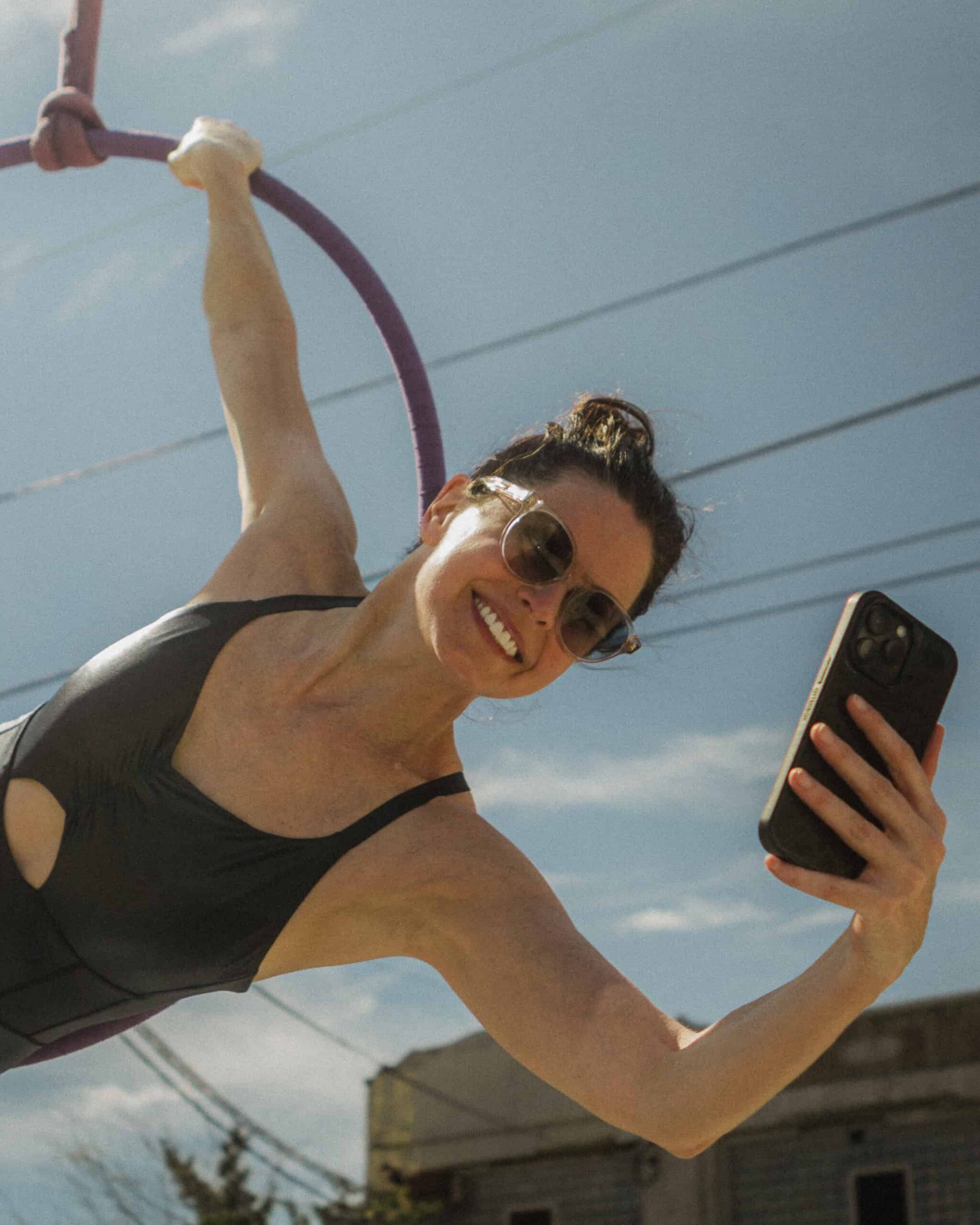 Woman on lyra smiling and holding a phone to take a selfie